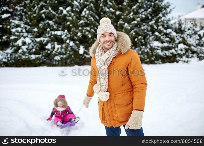 childhood, sledding, leisure, season and people concept - happy man or father carrying little kid on sled in winter