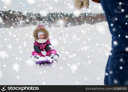childhood, sledding, leisure, season and people concept - parent carrying happy little kid on sled in winter