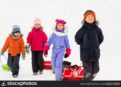 childhood, sledging and season concept - group of happy little kids with sleds in winter. happy little kids with sleds in winter