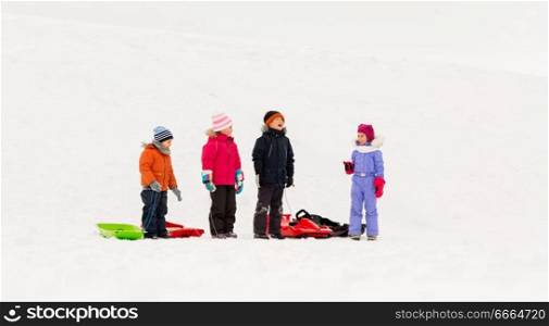 childhood, sledging and season concept - group of happy little kids with sleds in winter. happy little kids with sleds in winter