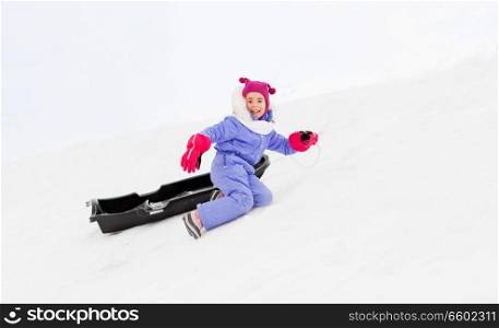 childhood, sledging and winter season concept - happy little girl with sled on snow hill. little girl with sled on snow hill in winter