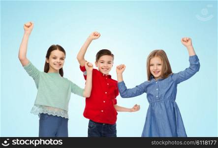 childhood, success, gesture and people concept - happy smiling boy and girls raising fists and celebrating victory over blue background