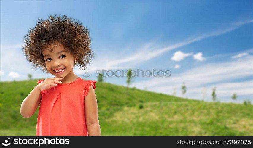 childhood, summer and people concept - happy little african american girl over green meadow and blue sky background. happy little african american girl in summer