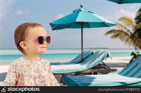 childhood, summer and people concept - happy little baby girl in sunglasses over tropical beach background in french polynesia. happy baby girl in sunglasses on summer beach