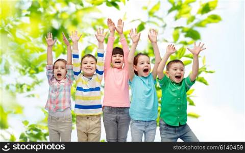 childhood, summer, fashion, gesture and people concept - happy smiling friends raising fists and celebrating victory over green natural background