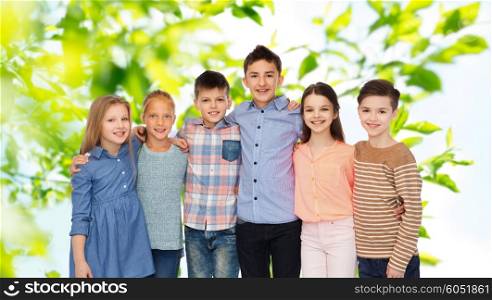 childhood, summer, friendship and people concept - happy smiling children hugging over green natural background