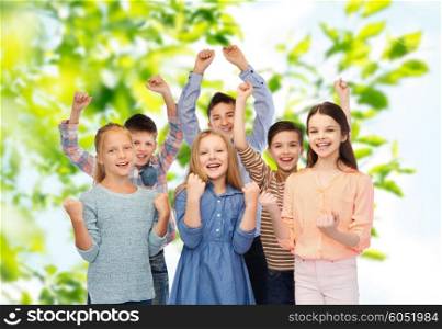 childhood, summer, gesture and people concept - happy children friends raising fists and celebrating victory over green natural background