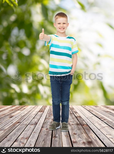 childhood, summer, gesture and people concept - smiling little boy showing thumbs up over plants and wooden floor background