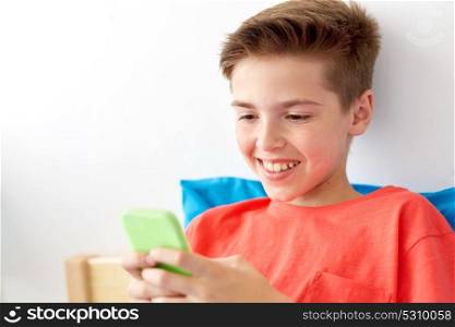 childhood, technology and communication concept - close up of happy smiling boy with smartphone at home. happy smiling boy with smartphone at home