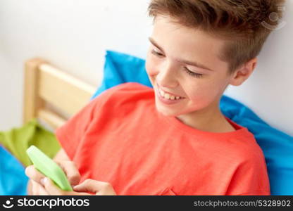 childhood, technology and communication concept - close up of happy smiling boy with smartphone at home. close up of happy boy with smartphone at home