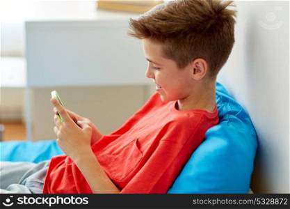 childhood, technology and communication concept - happy smiling boy with smartphone at home. happy smiling boy with smartphone at home