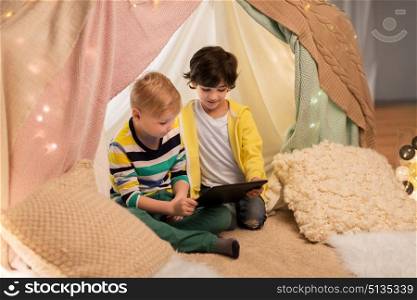 childhood, technology and hygge concept - happy little boys with tablet pc computer in kids tent at home. little boys with tablet pc in kids tent at home. little boys with tablet pc in kids tent at home