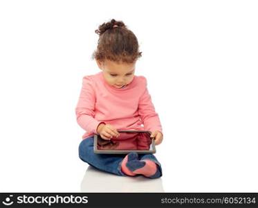 childhood, technology and people concept - little african american baby girl playing with tablet pc computer and sitting on floor