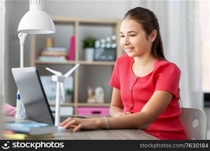 childhood, technology and people concept - smiling teenage girl with laptop computer and wind turbine toy at home. girl with laptop and wind turbine toy at home