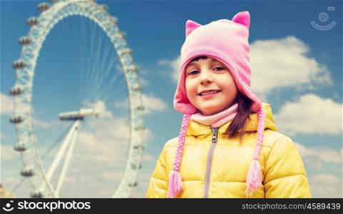 childhood, tourism, travel, vacation and people concept - happy beautiful little girl over london ferry wheel background