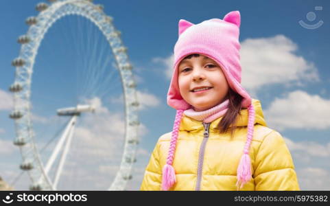 childhood, tourism, travel, vacation and people concept - happy beautiful little girl over london ferry wheel background