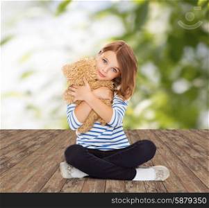 childhood, toys and people concept - cute little girl hugging teddy bear over greed background