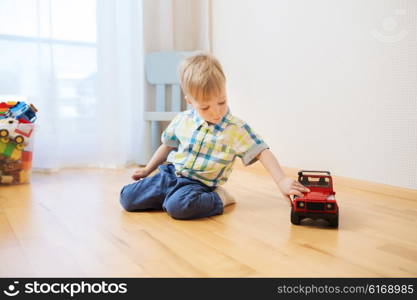 childhood, toys and people concept - little baby boy toy playing with car at home