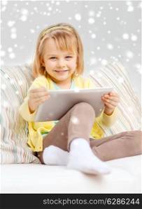 childhood, toys, technology and happiness concept - smiling little girl with tablet pc computer sitting on sofa at home
