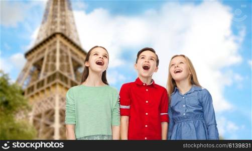 childhood, travel, tourism, friendship and people concept - happy amazed boy and girls looking up with open mouths over paris eiffel tower background