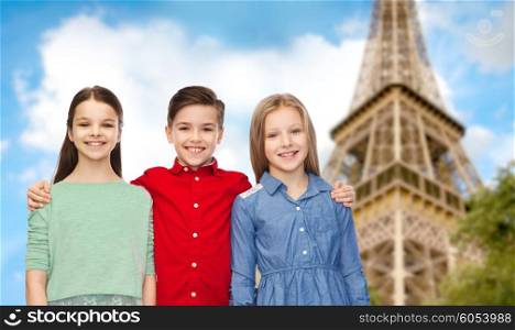 childhood, travel, tourism, friendship and people concept - happy smiling boy and girls hugging over paris eiffel tower background