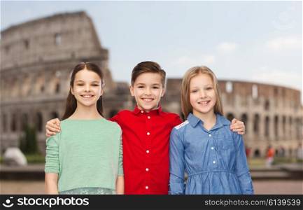 childhood, travel, tourism, friendship and people concept - happy smiling boy and girls hugging over coliseum in rome