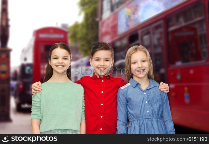 childhood, travel, tourism, friendship and people concept - happy smiling boy and girls hugging over london city street background