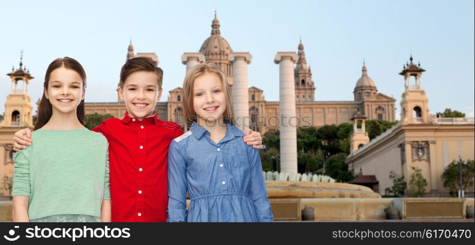 childhood, travel, tourism, friendship and people concept - happy smiling boy and girls hugging over national museum of barcelona background