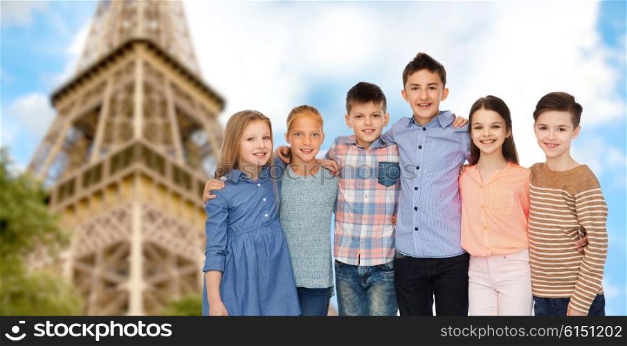 childhood, travel, tourism, friendship and people concept - happy smiling children hugging over paris eiffel tower background