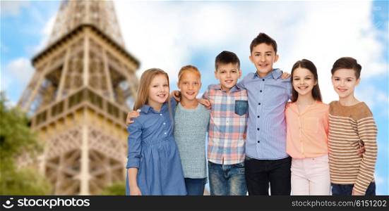 childhood, travel, tourism, friendship and people concept - happy smiling children hugging over paris eiffel tower background