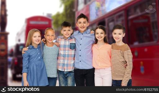 childhood, travel, tourism, friendship and people concept - happy smiling children hugging over london city street background