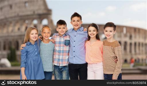 childhood, travel, tourism, friendship and people concept - happy smiling children hugging over coliseum in rome
