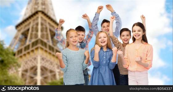 childhood, travel, tourism, gesture and people concept - happy children friends raising fists and celebrating victory over paris eiffel tower background