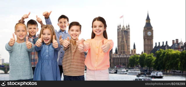 childhood, travel, tourism, gesture and people concept - happy smiling children showing thumbs up over london city background