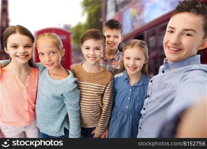 childhood, travel, tourism, technology and people concept - happy children talking selfie over london city street background