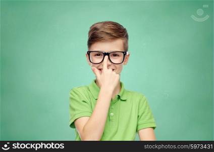 childhood, vision, school, education and people concept - happy smiling boy in green polo t-shirt in eyeglasses over green school chalk board background