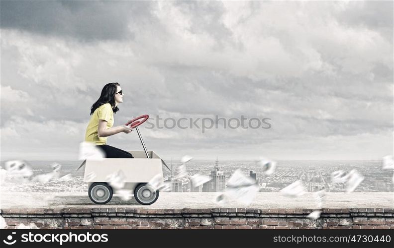 Childish adults. Young funny woman riding in carton box