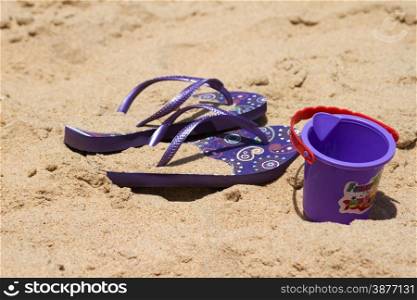 Children&#39;s sandy toys and flip-flop on a beautiful beach. India Goa.