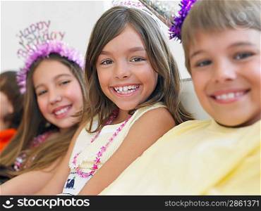 Children (7-12) sitting in row at birthday party selective focus