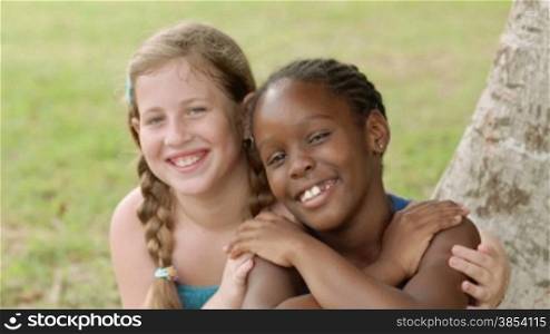 Children and friendship, portrait of two young girls hugging, smiling and looking at camera