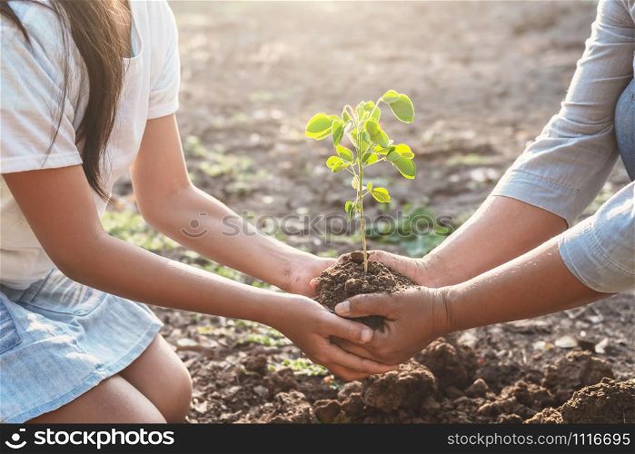 children and mom helping planting young tree. eco concept