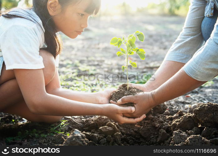 children and mom helping planting young tree. eco concept