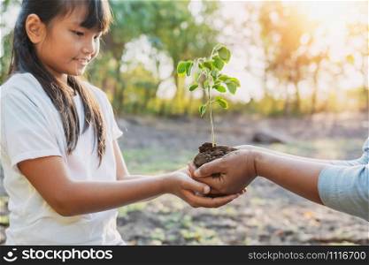 children and mom helping planting young tree. eco concept