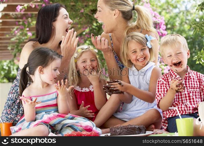 Children And Mothers Eating Jelly And Cake At Outdoor Tea Party