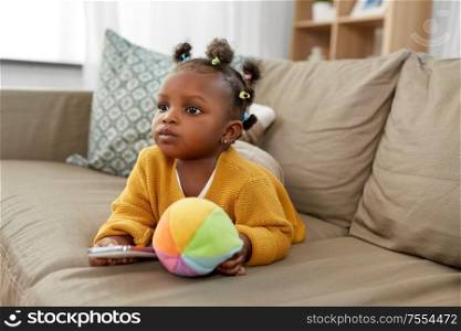 children and technology concept - lovely african american baby girl with smartphone and toy ball at home. african american baby girl with smartphone at home