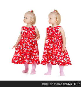 children and twins concept - two identical twin girls in red dresses looking somewhere
