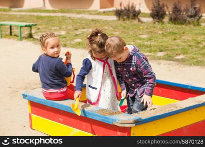 Children are playing at the playground with sand in the sandbox