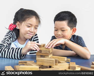 Children are playing jenga, a wood blocks tower game for practicing their physical and mental skill