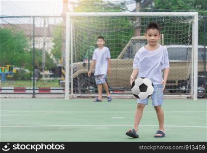 Children are wearing slippers playing football With blurred background to show movement.To exercise After school.