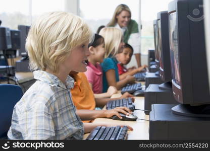 Children at computer terminals with teacher in background (depth of field/high key)